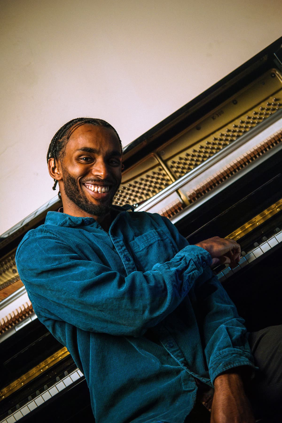 Judah laughing at an upright piano, turned towards the camera